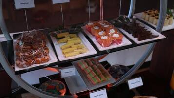 A display case with various baked goods including doughnuts, pan cakes, and sandwiches.