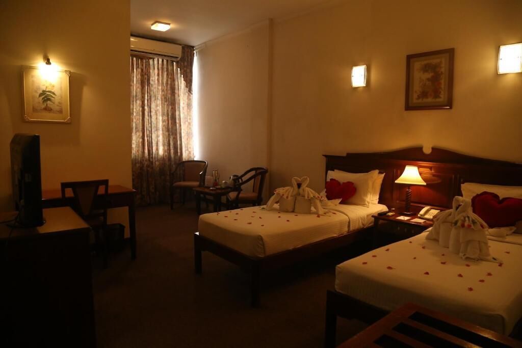 Une chambre d’hôtel avec deux lits, un bureau, une chaise et un téléviseur.