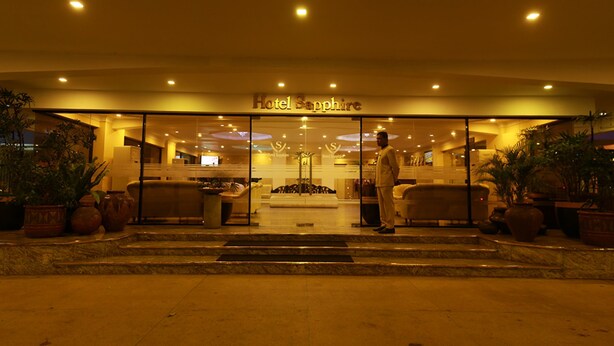 The entrance of Hotel Sapphire with a modern design, featuring a glass facade, a welcoming reception area, and potted plants. - Hotel Sapphire (Colombo)