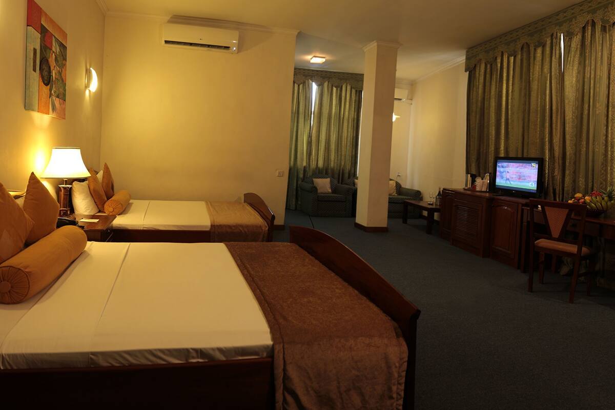 Una habitación de hotel con dos camas, un escritorio, un televisor y una zona de comedor.