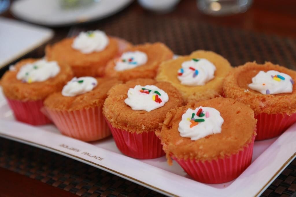Uma bandeja de cupcakes com cobertura branca e granulado colorido.