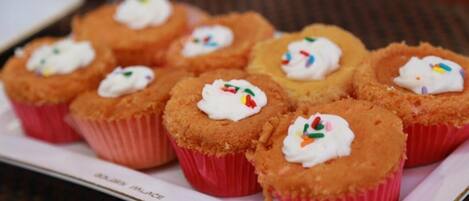 A tray of cupcakes with white frosting and colorful sprinkles.