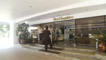 La entrada del Hotel Sapphire, con escalones de mármol y plantas en macetas.