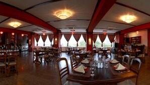 A spacious restaurant with high ceilings, chandeliers, and large windows. Tables are set with white tablecloths and red napkins. - Hotel Sapphire (Colombo)