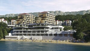 A coastal hotel with multiple buildings, a beach with sun loungers, and a mountainous backdrop. - Hotel Labineca (Gradac)