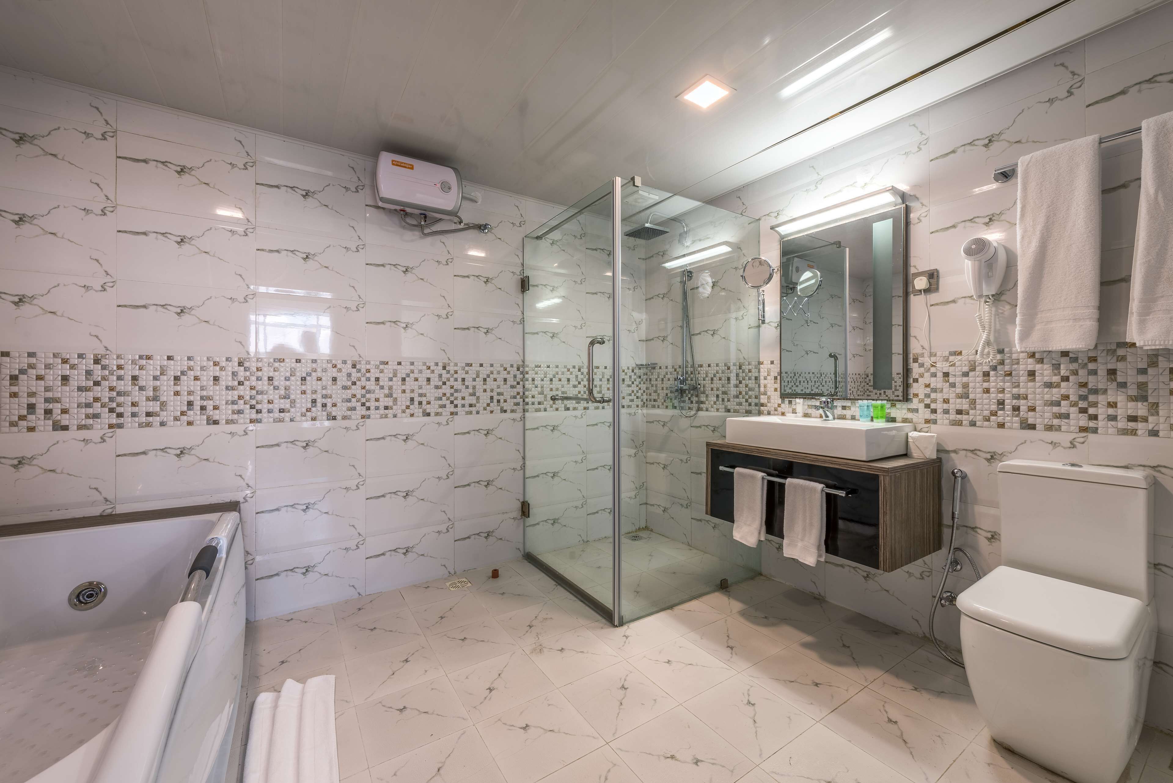 A modern bathroom with a glass-enclosed shower, a bathtub, a toilet, and a vanity with a mirror and towel rack.