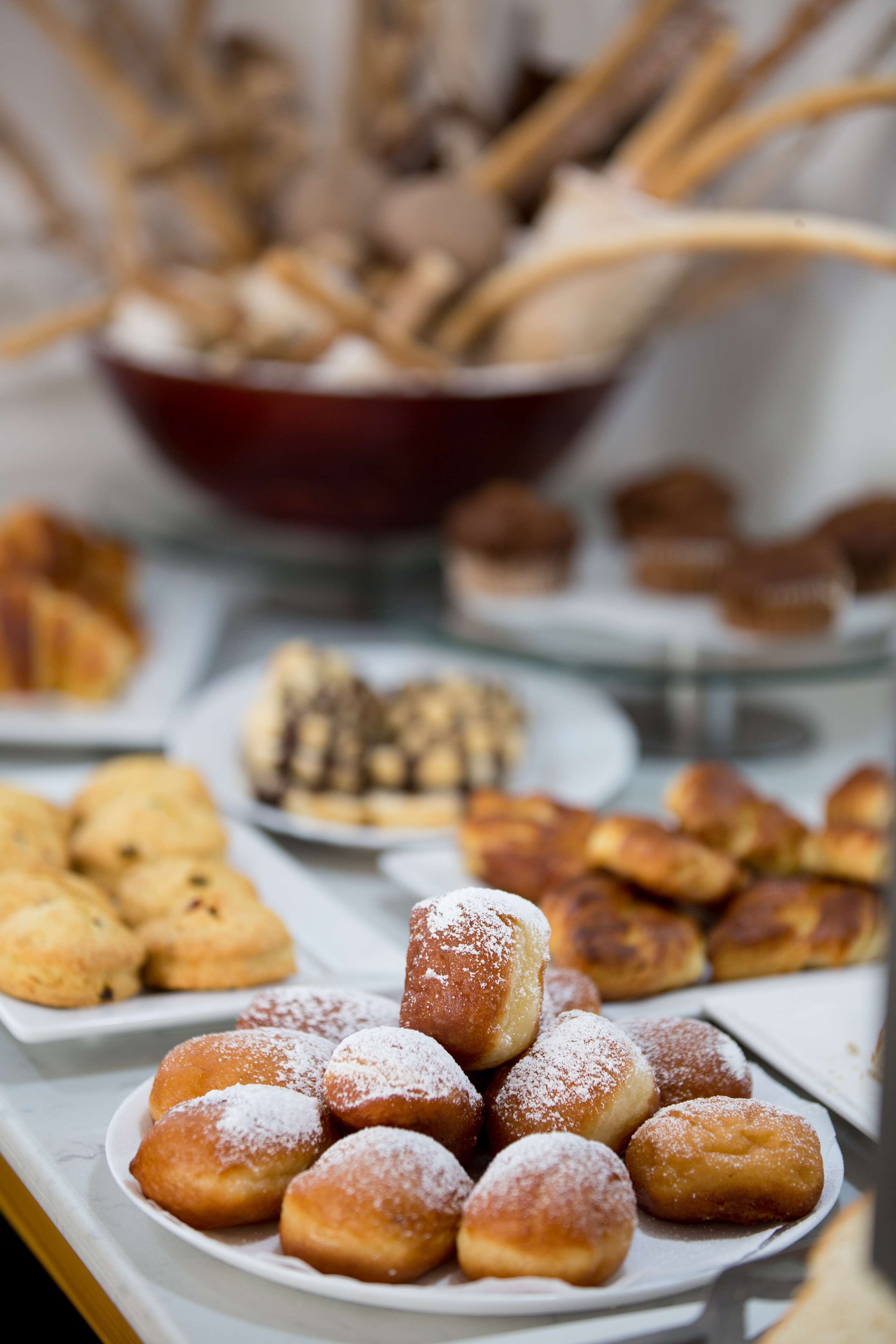 Un bufé con diversos pasteles y postres, entre ellos rosquillas y muffins.