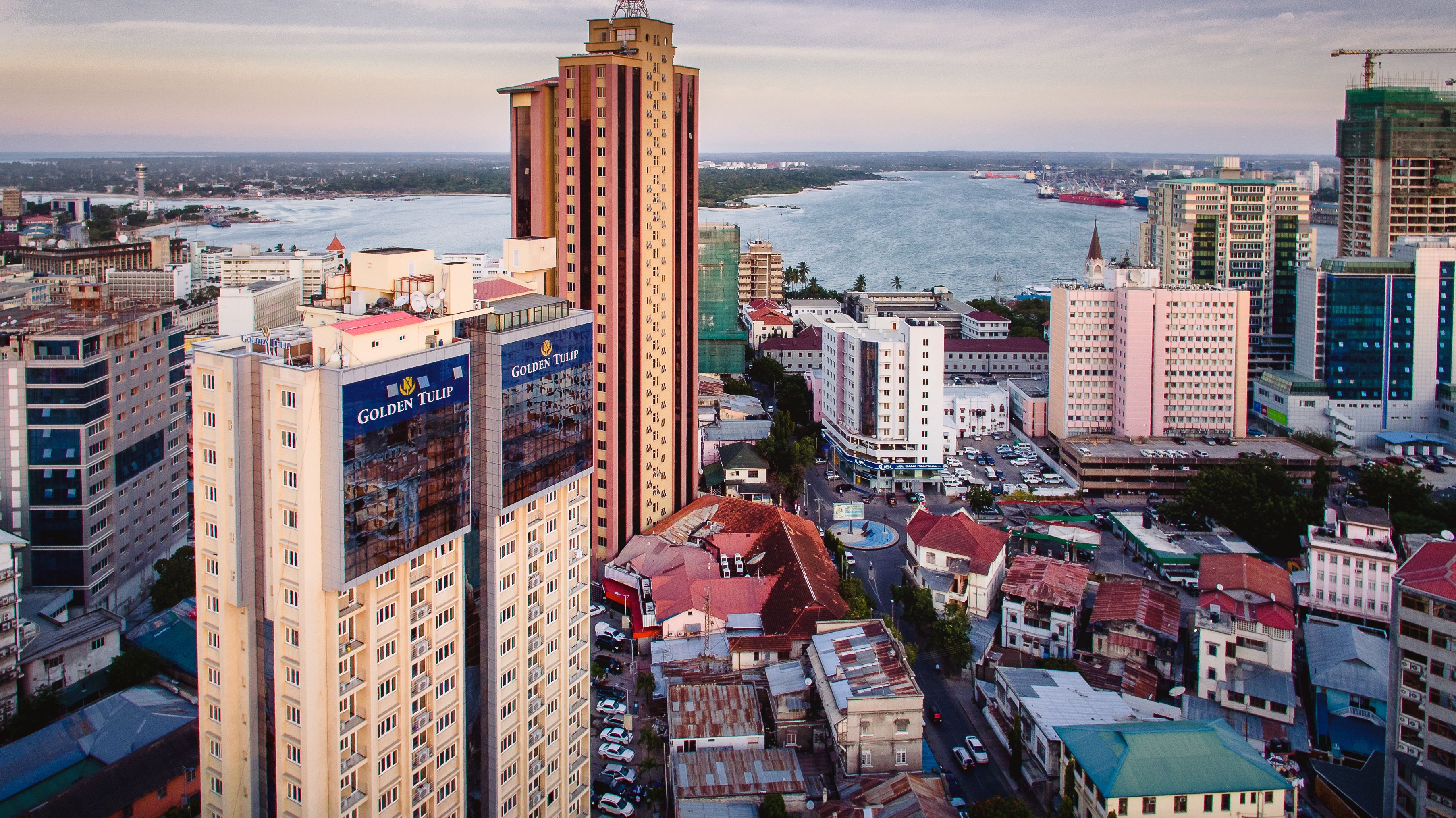 Un immeuble de grande hauteur, reconnaissable à son grand panneau « Golden Tulip », entouré d’autres bâtiments et offrant une vue sur la mer.