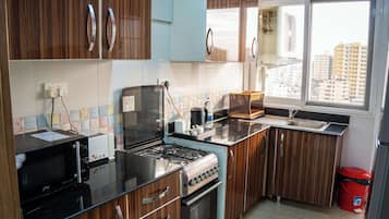 Una cocina moderna con gabinetes de madera, estufa a gas, microondas y un lavamanos.