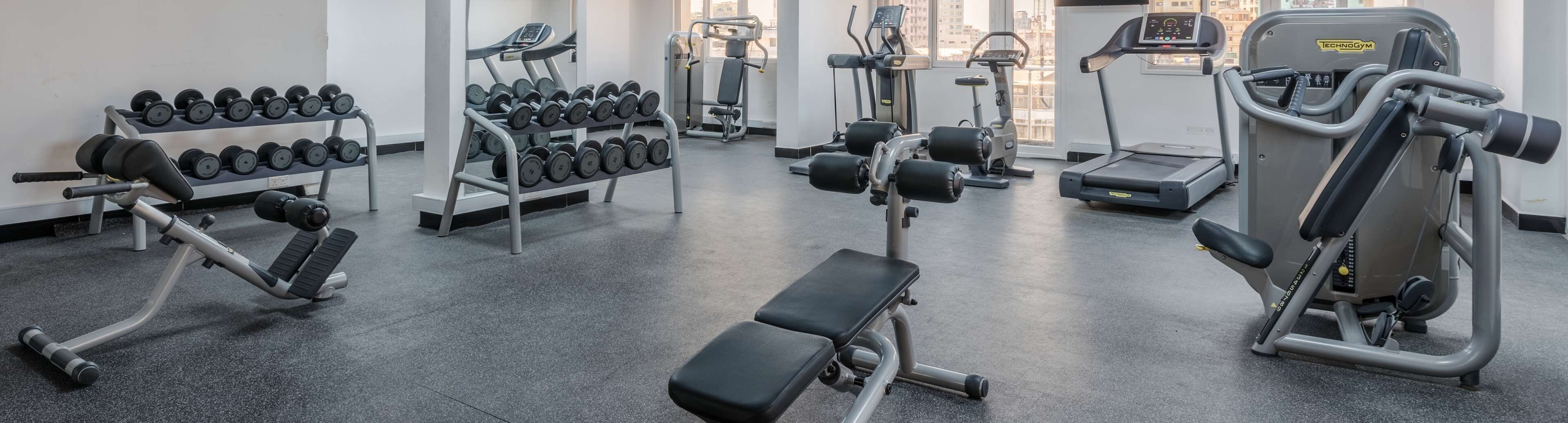 A gym with various exercise equipment including dumbbells, treadmills, and weight machines.