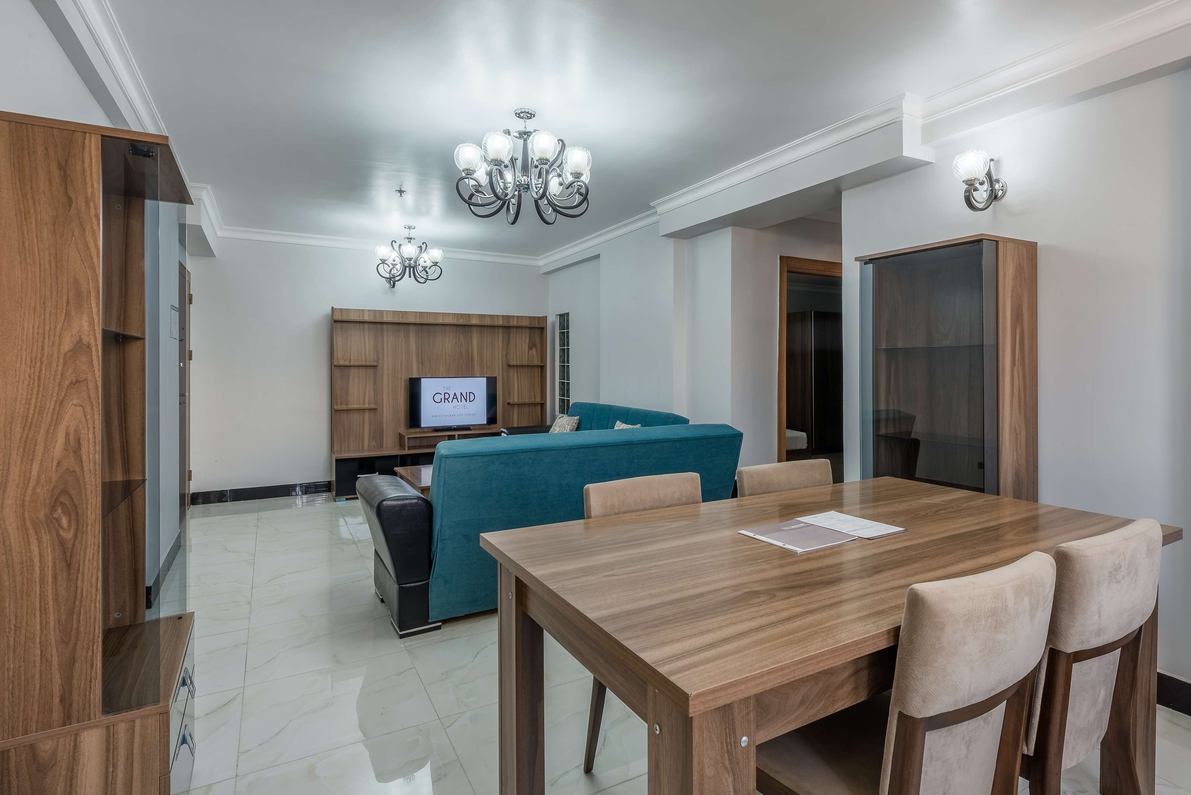Una sala de estar moderna con una mesa de comedor de madera, un sofá azul aguamarina y un televisor sobre un mueble de madera.