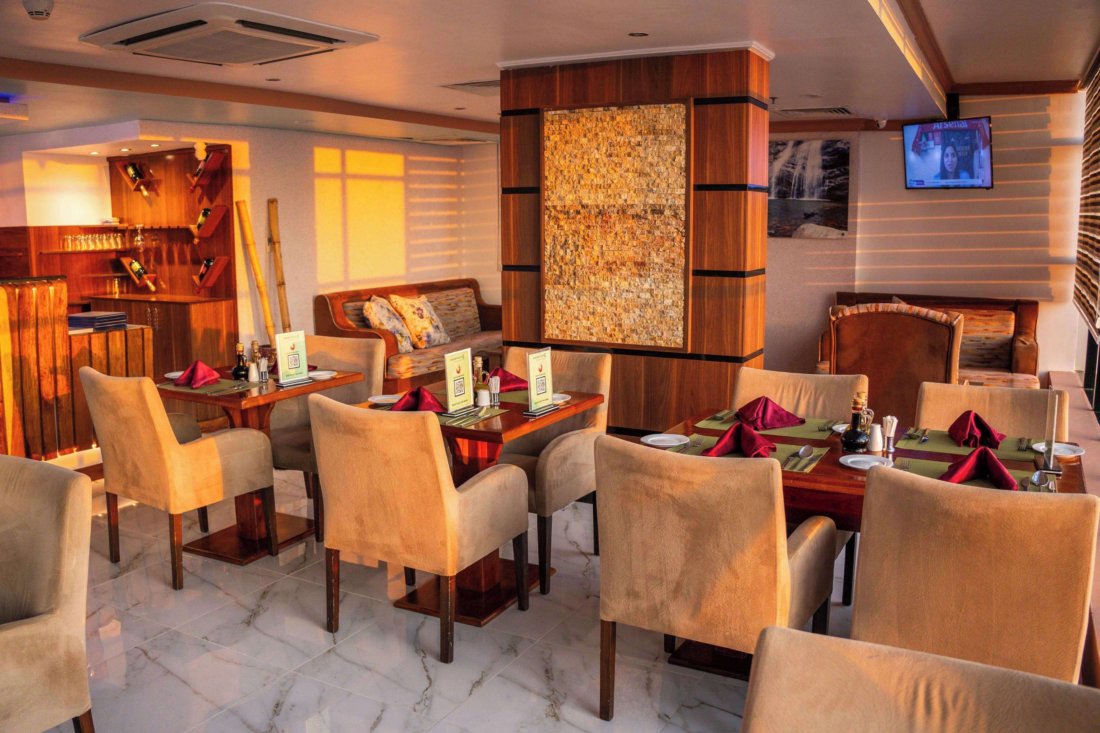 Un restaurante con muebles de madera, un televisor montado en la pared y un cuadro abstracto grande.