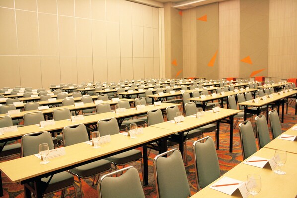 Un salón de conferencias con filas de mesas, sillas y placas de identificación.