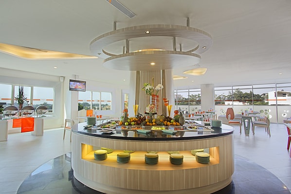 Un moderno vestíbulo de hotel con una zona de bar circular central, arreglos de asientos y grandes ventanales que ofrecen vistas.