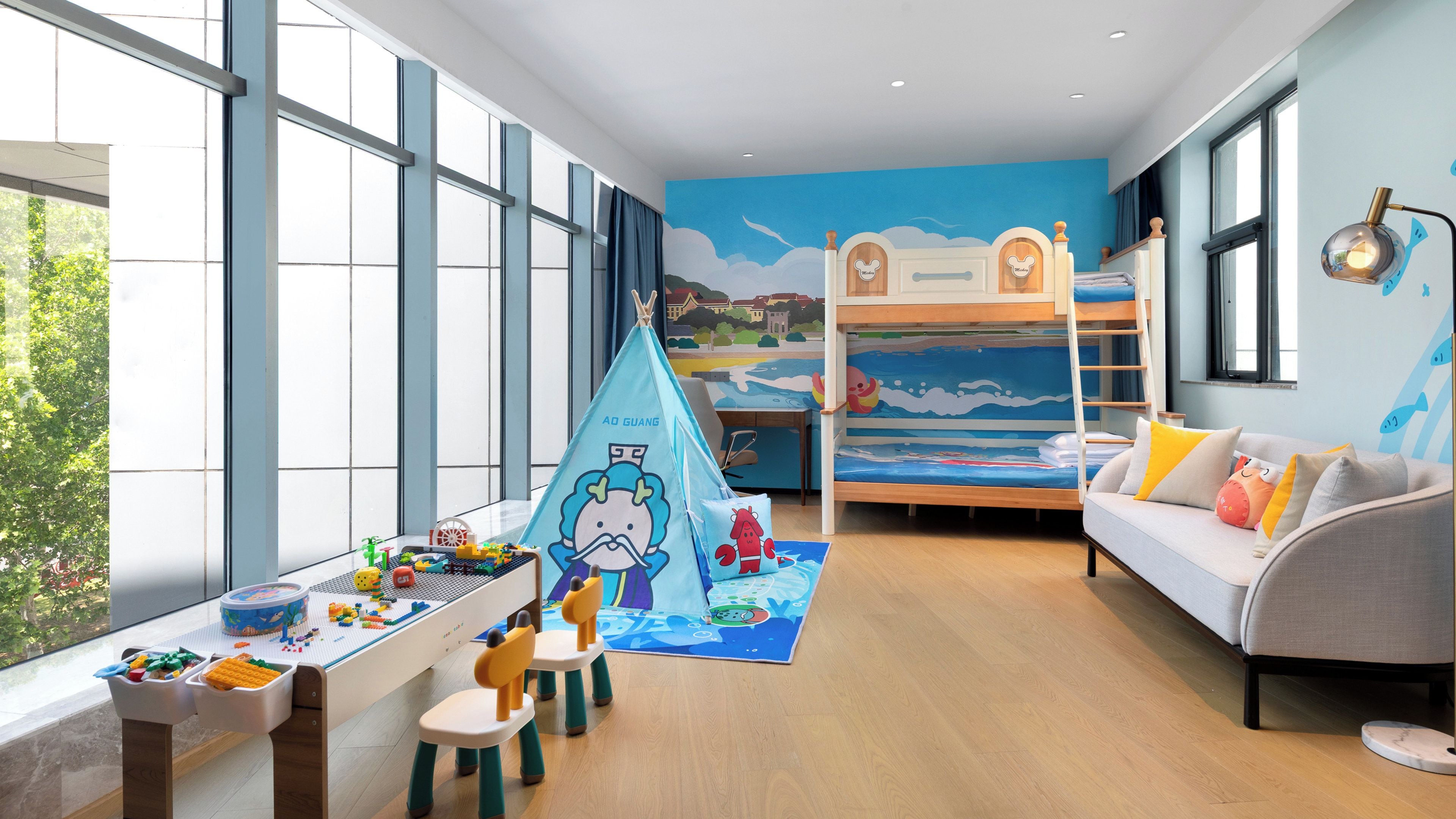 Een kinderkamer met een stapelbed, een bureau vol speelgoed en een bank.