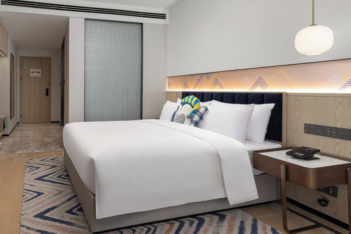 Une chambre d’hôtel avec un lit, une table de chevet et une petite table d’appoint.