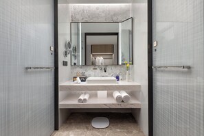 Features a sleek sink, large mirror, scale, and neatly rolled towels.