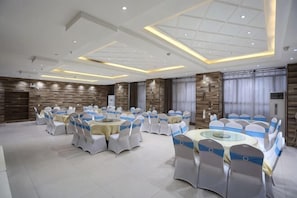 Un salón de banquetes con mesas y sillas redondas, iluminación empotrada y un diseño de techo moderno.