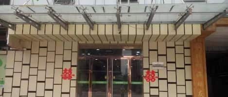 A hotel entrance with a modern facade, a glass door, and a sign with Chinese characters.