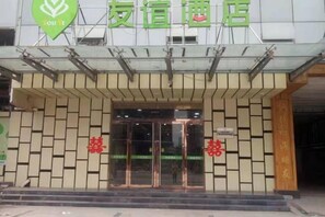 A hotel entrance with a modern facade, a glass door, and a sign with Chinese characters.