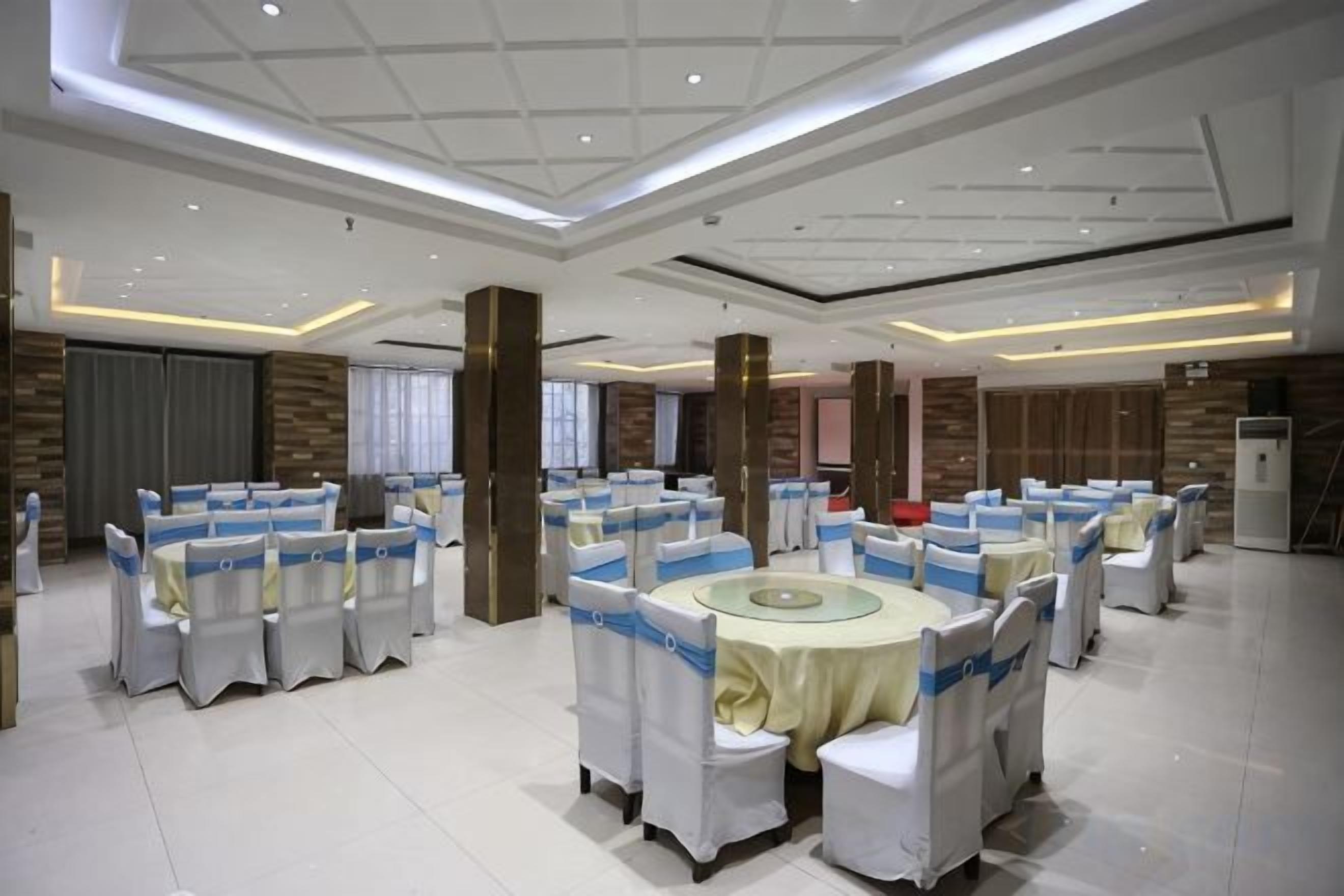 A banquet hall with round tables and chairs, a high ceiling, and a modern design.