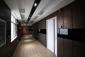 A corridor with wooden flooring, a door, and a wall-mounted sign. - Zhaoxian Friendship Hotel (Zhao County)