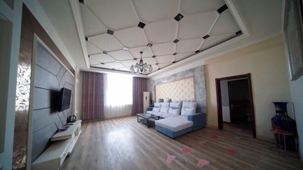 Una sala de estar moderna con un sofá modular, un televisor de pantalla plana y piso de madera.