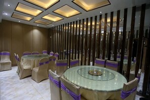 Une salle de conférence équipée de tables rondes, de chaises et d’un élément de séparation décoratif.