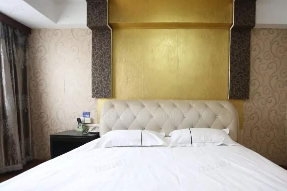 A hotel room with a large bed, a nightstand, and a wall with a decorative pattern.