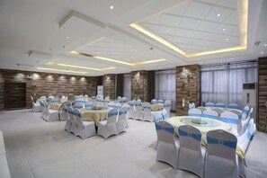 Un salón de banquetes con mesas y sillas redondas, iluminación empotrada y un diseño de techo moderno.
