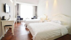Una camera d'albergo con due letti, una scrivania, una sedia e una televisione.