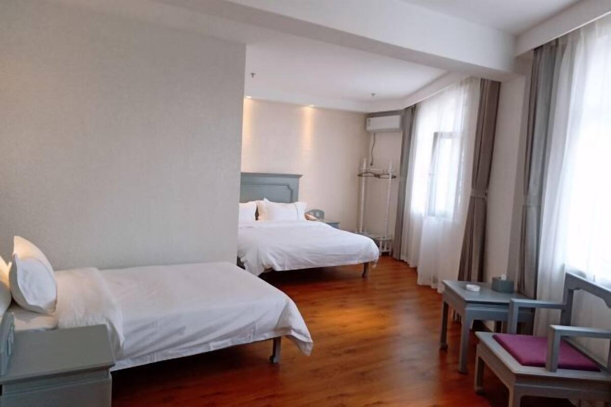 A hotel room with two beds, a desk, a chair, and a window with curtains.