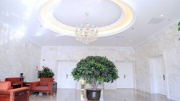 A lobby with a chandelier, a reception desk, and a potted plant.
