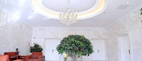 A lobby with a chandelier, a reception desk, and a potted plant.