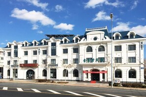 A multi-story building with a classical architectural style, featuring arched windows and a symmetrical facade. - Jinyuwan Hotel (Dalian Lvshun University Town) (Dalian)