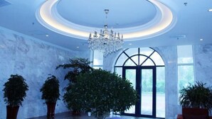 Un'ampia hall con un grande lampadario, pareti in marmo e ampie finestre.