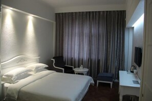 A hotel room with a bed, a desk, a chair, a small table, and a television. - Jinyuwan Hotel (Dalian Lvshun University Town) (Dalian)