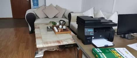 A room with a sofa, a coffee table, a printer, and a box of tissues.