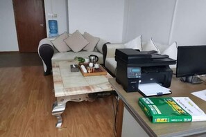 Una habitación con un sofá, una mesa de centro, una impresora y una caja de pañuelos.