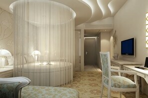Una habitación de hotel moderna con una cama redonda, un televisor, un escritorio y una silla.