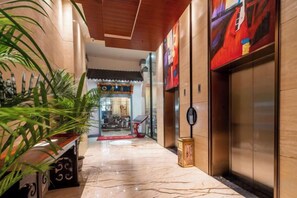 Un vestíbulo de hotel con piso de mármol, una recepción y un ascensor.
