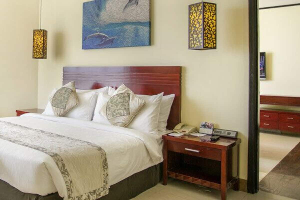 A hotel room with a large bed, a desk, a chair, and a view of the outdoors.