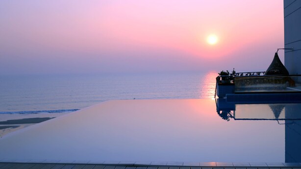 Een zonsondergang boven de zee, zichtbaar vanaf een overloopzwembad.