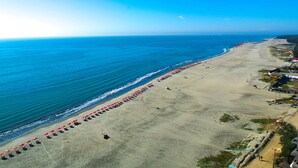 Een vogelperspectief van een strand met rijen parasols en mensen.