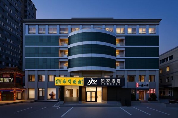Ett hotell med modern design, kännetecknat av en böjd fasad, flera balkonger och en framträdande entré med skyltar.