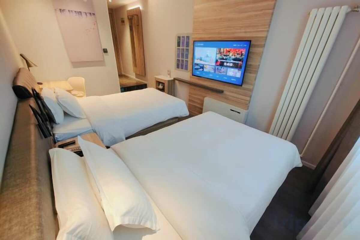 A hotel room with two beds, a television, and a wooden wall.