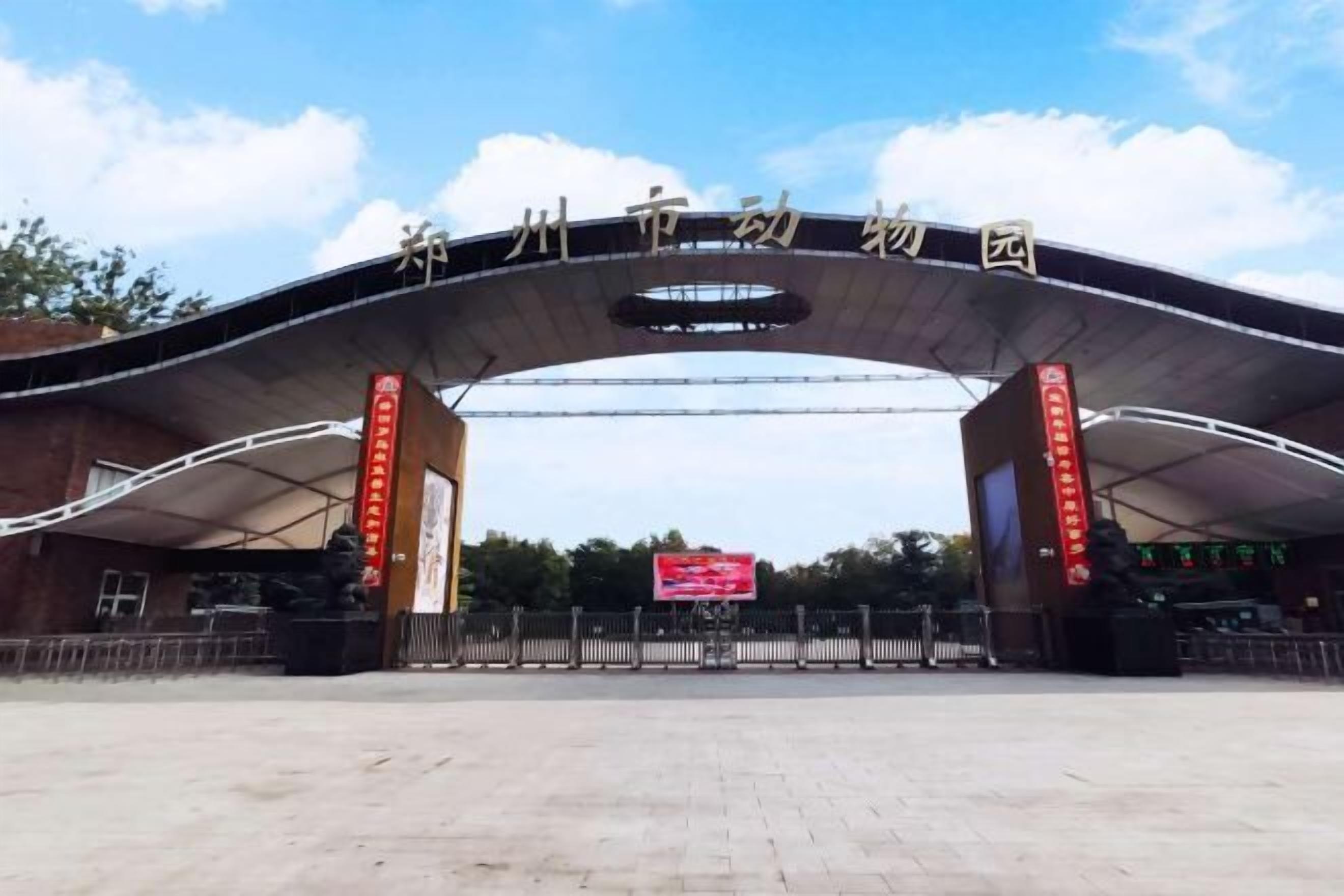 An entrance to a park with a large arched canopy and red banners.