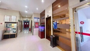 Un pasillo de hotel con una mesa de recepción, un contenedor de basura y un cartel que indica un restaurante.