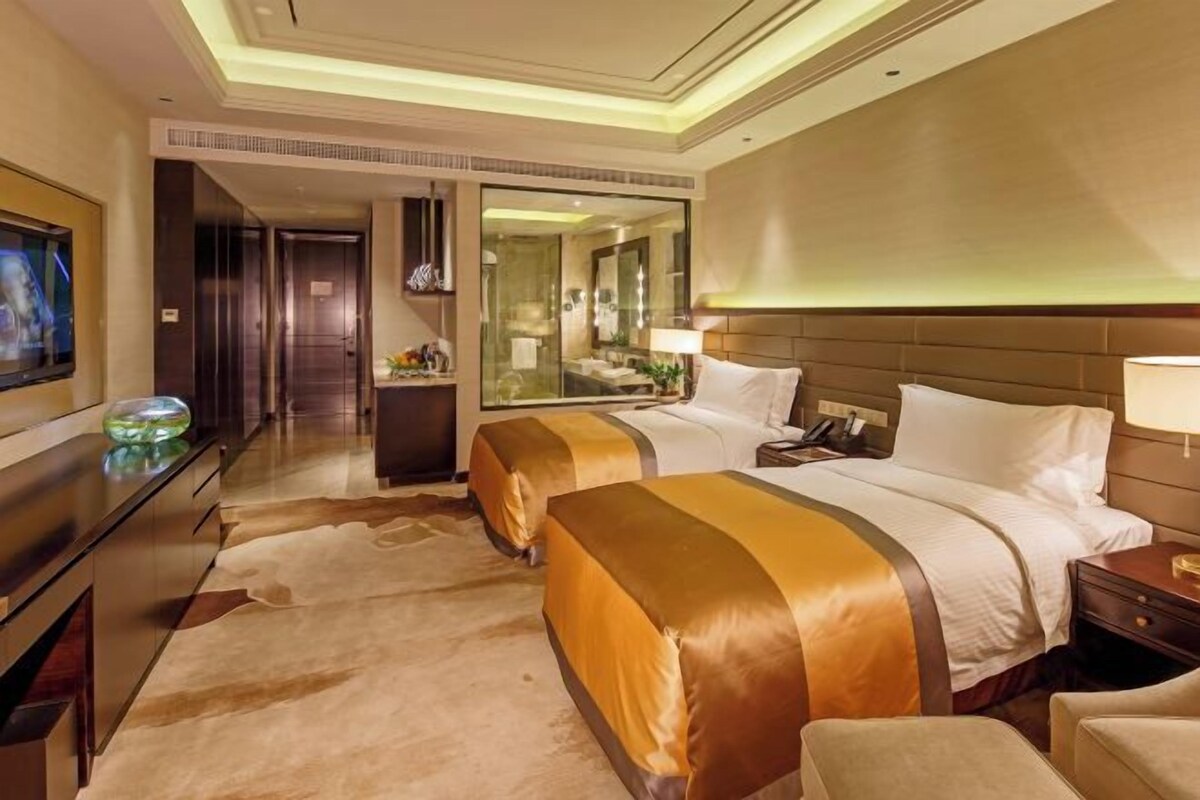 Habitación de hotel con una cama grande, un escritorio, un televisor y un espejo.