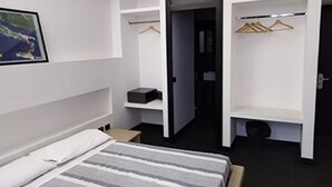 Une chambre à coucher moderne, comprenant un lit, une armoire avec espace pour suspendre les vêtements et une petite table de chevet.